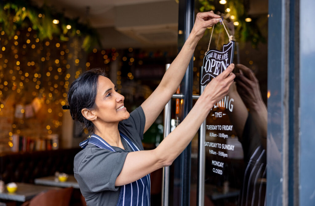 Small business restaurant owner hanging open sign on door. General Liability business example.